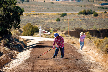Mazi Dressler and Cecelia Lopez, both in their 70's, rake a road near Rock Springs Friday. A group of five elderly residents pooled their money to pay for gravel and grading of the road after the tribe, county and BIA said there was no money for improvements. The residents were worried about the mud that comes with winter weather. © 2011 Gallup Independent / Brian Leddy 